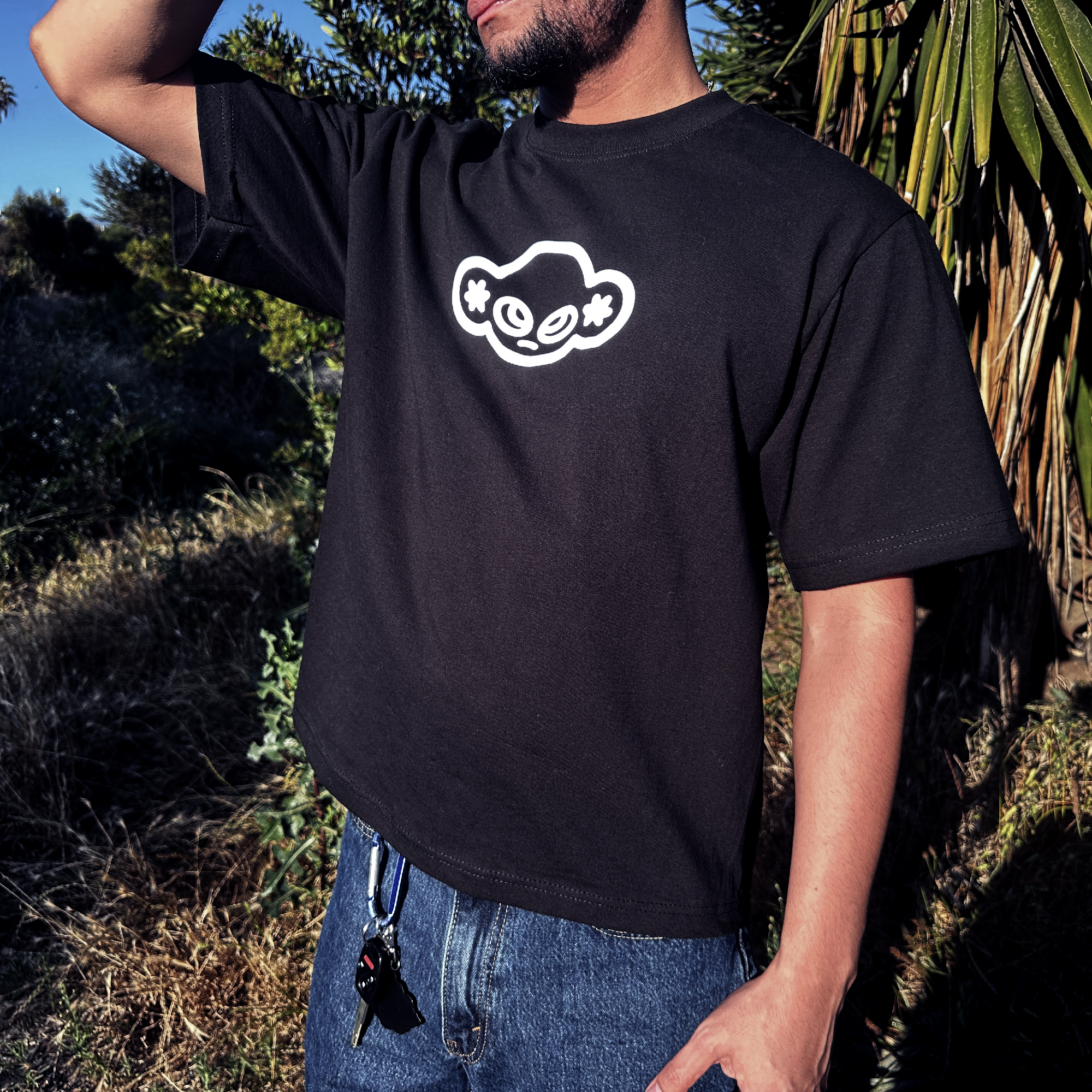 Person wearing a black t-shirt with a white graphic design outdoors.