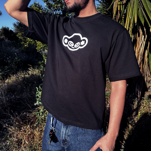Person wearing a black t-shirt with a white graphic design outdoors.
